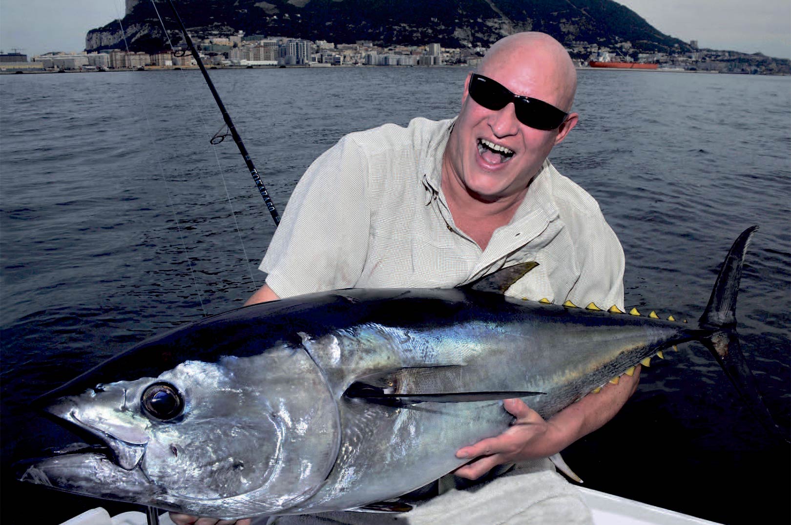 Johnny med en smuk 30 kilos fisk, der var lige ved at flå stangen ud afhånden på ham. I baggrunden ses Gibraltar klippen.