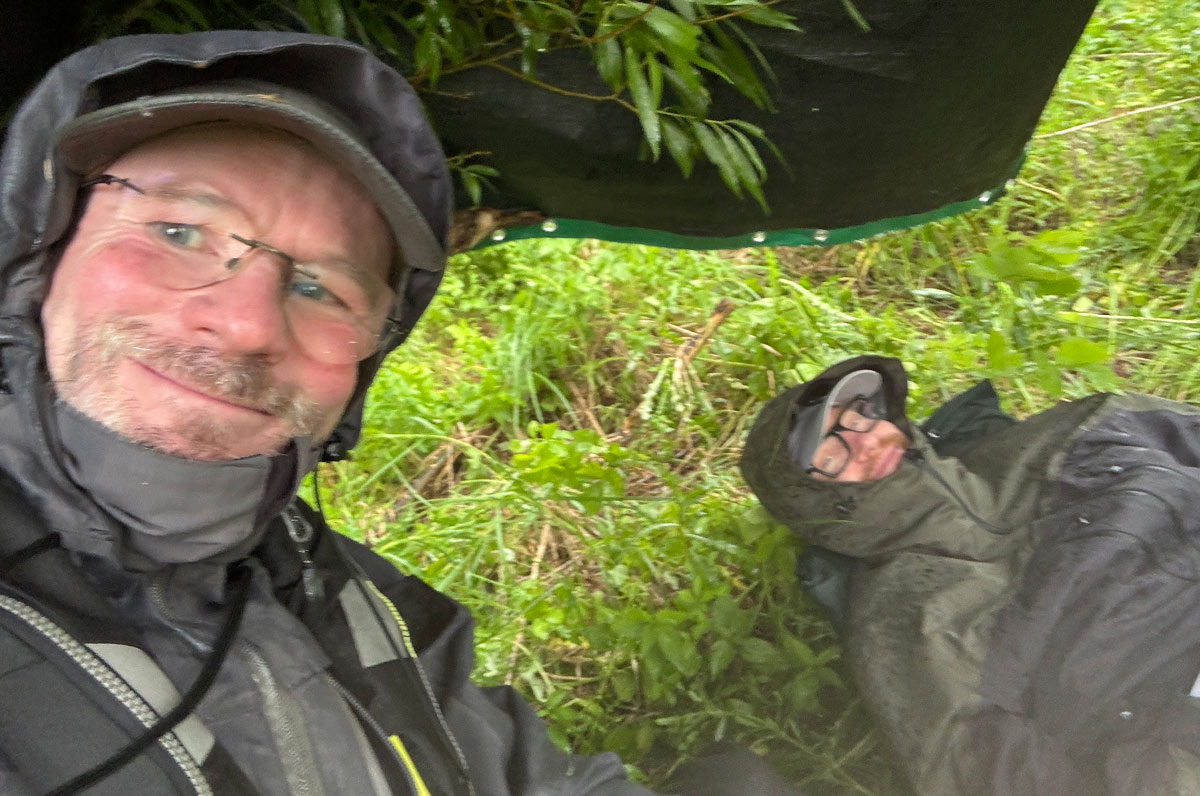 Jens og Søren øger ly under mallepressenningen under et pludseligt regnvejr - med vindstød op til 19 m/s der gjorde det umuligt at ffiske fra flyderingne.
