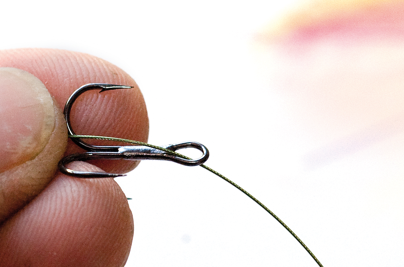 Sådan binder du en trekrogsnot-a-knot 1) Kør forfanget ind gennem øjet og læg den korte tamp parallelt med skaftet, så der stikker 8-10 cm ud bag krogen.